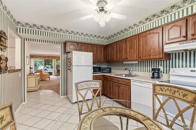 a kitchen with stainless steel appliances granite countertop a refrigerator a stove a sink dishwasher and white cabinets with wooden floor