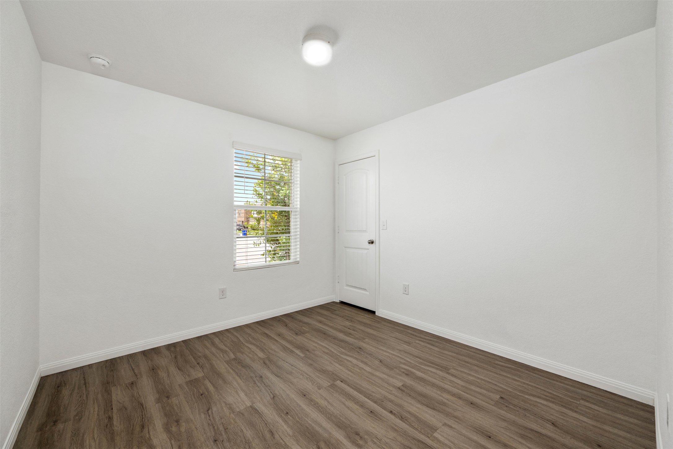 14900 Retha Pass Austin, TX 78725 - Photo 21 of 39 Room featuring wood-finish flooring, white baseboards, and a single window with horizontal blinds