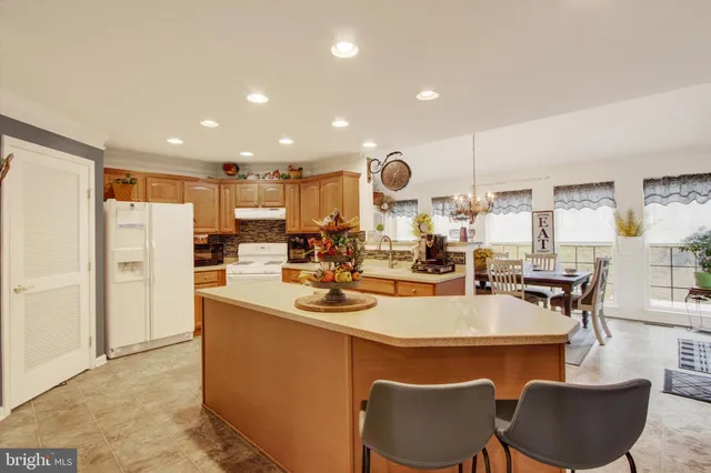 a kitchen with stainless steel appliances kitchen island granite countertop a table chairs and a refrigerator