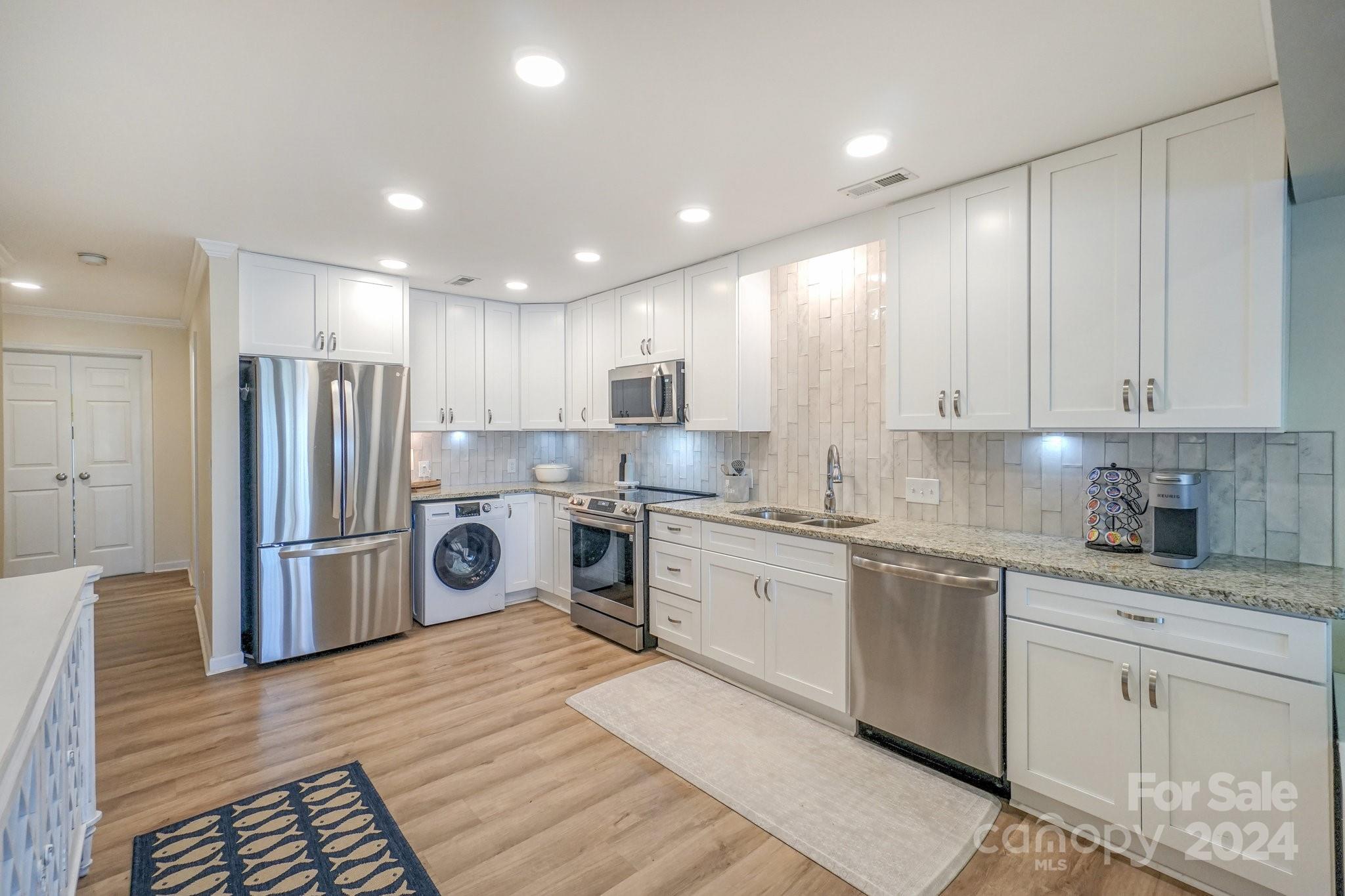 a kitchen with refrigerator a sink and white cabinets