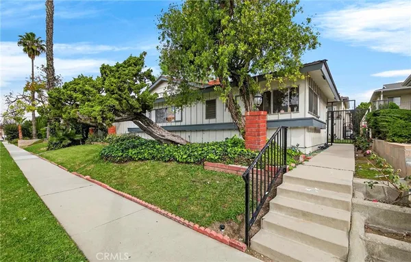 a front view of a house with a yard and potted plants