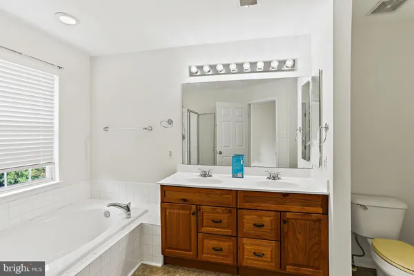a spacious bathroom with a granite countertop sink mirror and bathtub