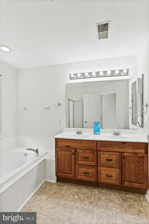 a spacious bathroom with a tub double sink and mirror