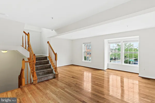 a view of an empty room with wooden floor and stairs