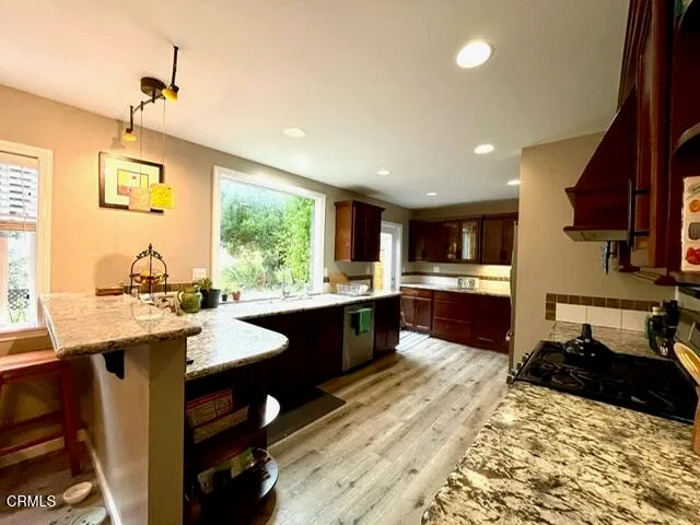 a large kitchen with stainless steel appliances granite countertop a sink dishwasher a stove a dining table and chairs with wooden floor