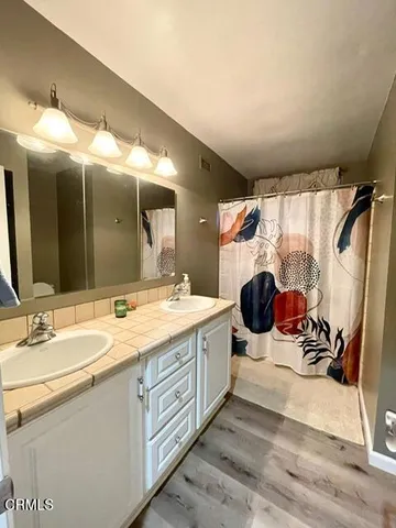 a bathroom with a double vanity sink mirror and shower