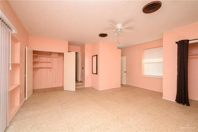 an empty room with closet and windows