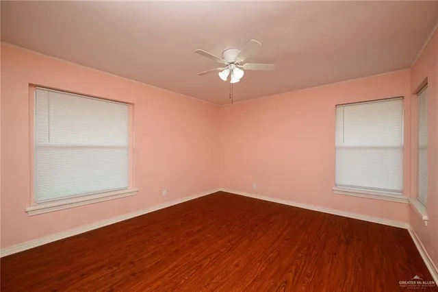 an empty room with wooden floor closet and fan