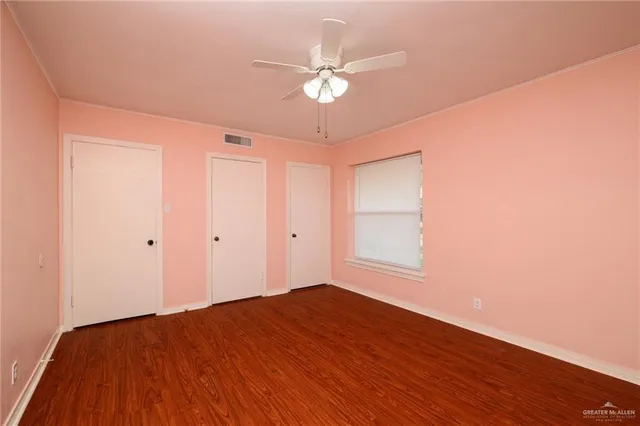 a view of a room with wooden floor and a ceiling fan