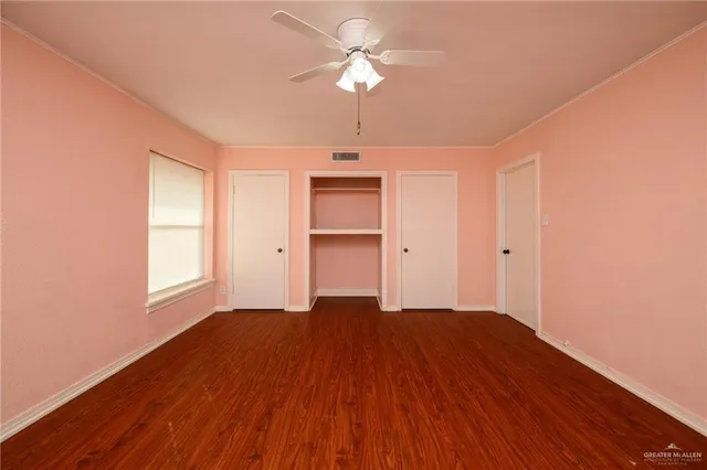 a view of an empty room with window and wooden floor