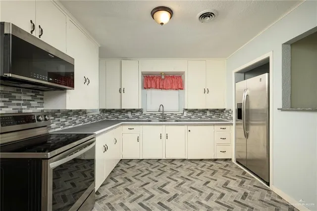 a kitchen with granite countertop a sink stove and refrigerator