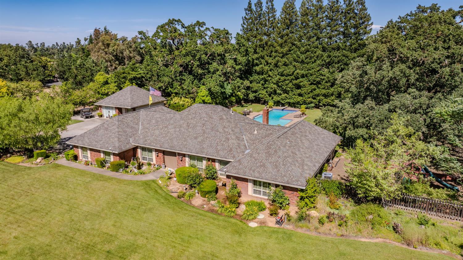 9069 Bader Road Elk Grove, CA 95624 - Photo 5 of 70 Brick exterior residence with a shingle roof, featuring an expansive front lawn, mature perimeter trees, a detached garage structure (Rec Room), and a backyard swimming pool with a surrounding patio