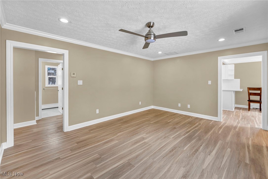 1447 East Sprague Road Independence, OH 44131 - Photo 18 of 47 Spare room with crown molding, a textured ceiling, ceiling fan, and light hardwood / wood-style flooring