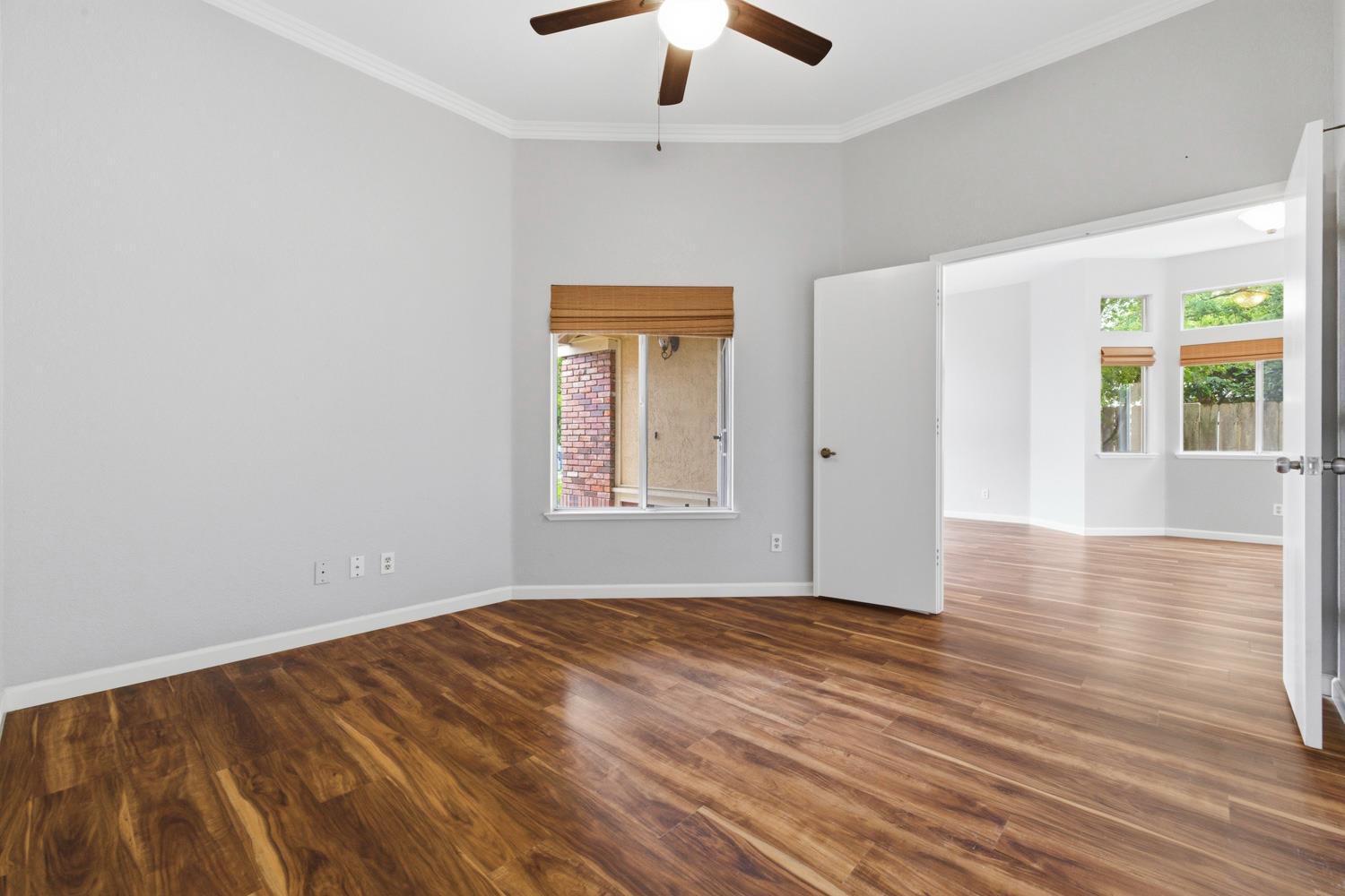 969 Colson Way Galt, CA 95632 - Photo 8 of 38 an empty room with wooden floor chandelier fan and windows