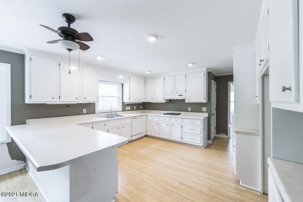 225 Beacon Hill Road Macon, GA 31210 - Photo 13 of 29 a large kitchen with a refrigerator a stove top oven a white counter space and cabinets