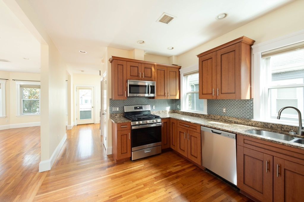 148 Albion Street, Unit 2 Somerville, MA 02144 - Photo 5 of 21 a kitchen with stainless steel appliances granite countertop a sink and wooden cabinets
