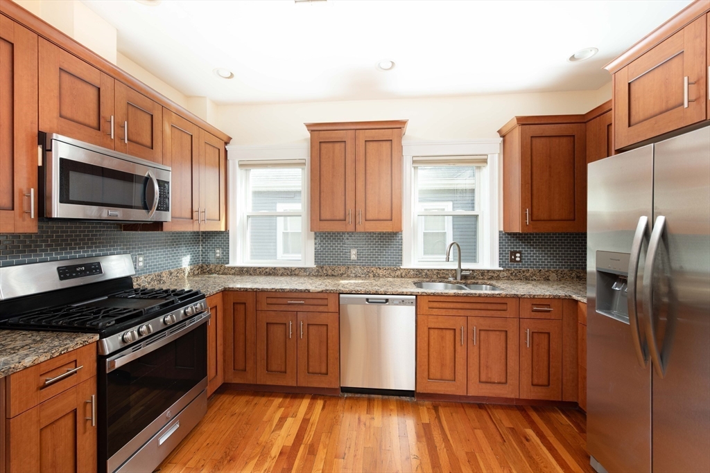 148 Albion Street, Unit 2 Somerville, MA 02144 - Photo 6 of 21 a kitchen with stainless steel appliances granite countertop a stove a sink dishwasher a refrigerator and a microwave oven with wooden floor