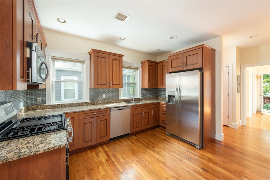 148 Albion Street, Unit 2 Somerville, MA 02144 - Photo 7 of 21 a kitchen with granite countertop a refrigerator and wooden cabinets