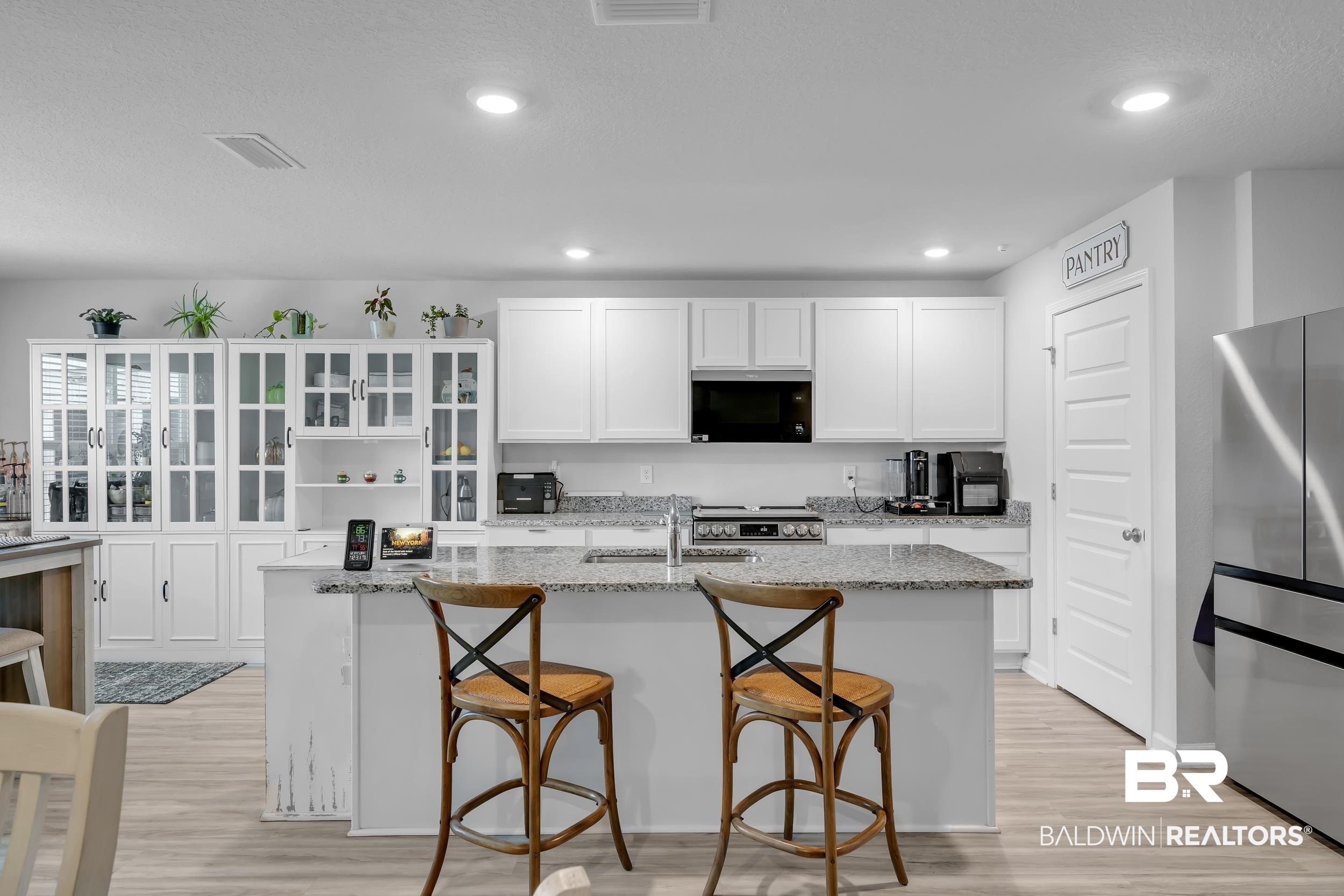 24271 Ringneck Loop Elberta, AL 36530 - Photo 18 of 44 Bright kitchen featuring white cabinetry, a central island with a granite-style countertop, stainless steel appliances, and wood-finish flooring