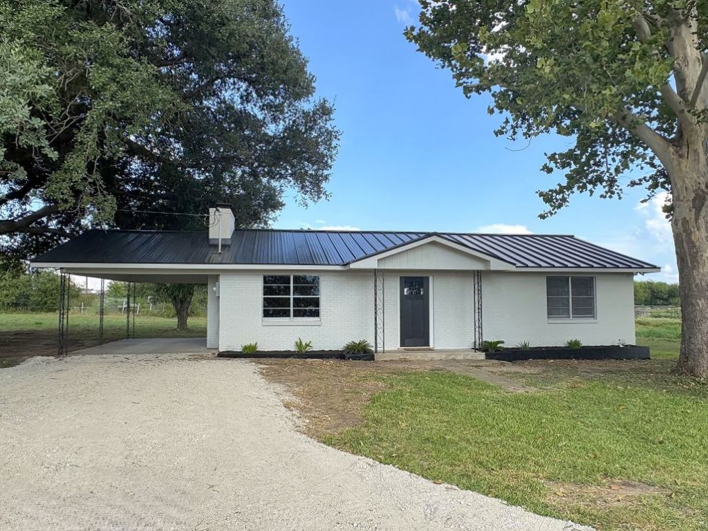 1304 Cr 215 Road Cameron, TX 76520 - Photo 1 of 1 Single story home featuring a metal roof, gravel driveway, a front lawn, and attached carport