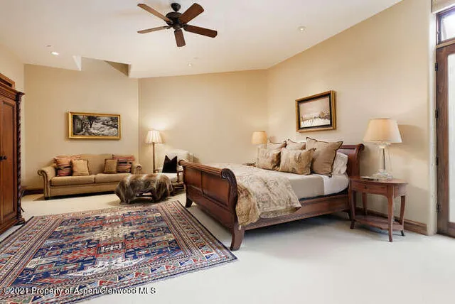 a spacious bedroom with a bed a couch and paintings on the wall