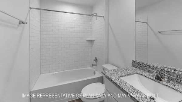a bathroom with a granite countertop bathtub shower sink vanity and toilet
