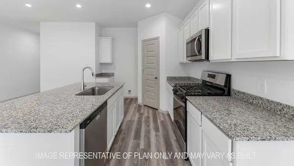 a kitchen with kitchen island granite countertop a sink a counter top space stainless steel appliances and cabinets