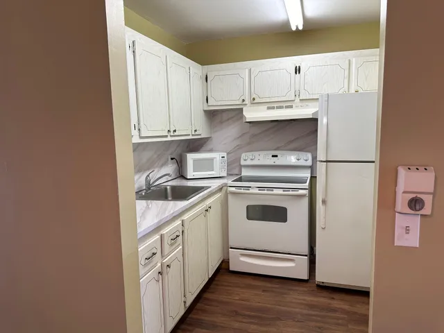 a kitchen with white cabinets and white appliances