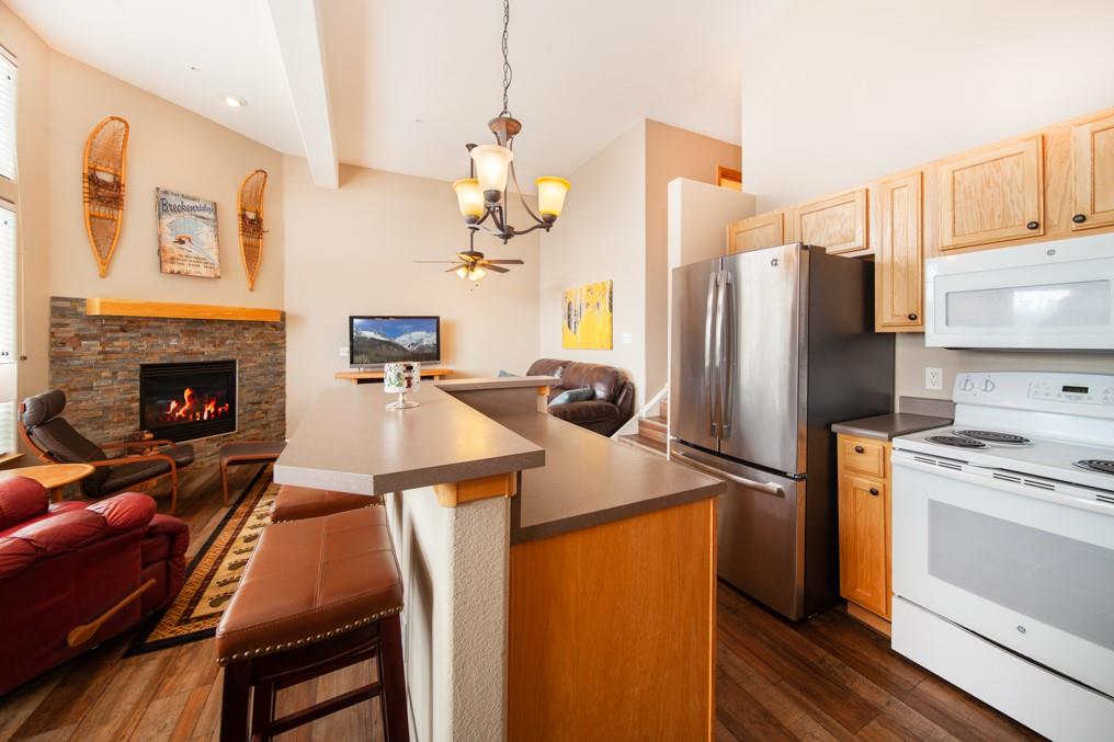 91199 Ryan Gulch Road, Unit A5 Silverthorne, CO 80498 - Photo 3 of 31 a kitchen with kitchen island a stove a refrigerator and a fireplace with wooden floor