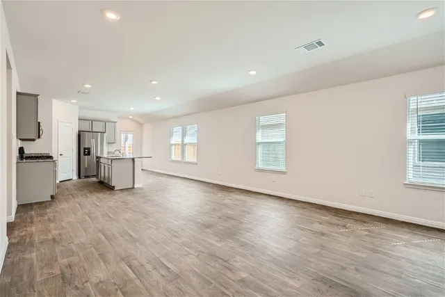 a view of empty room with wooden floor and windows