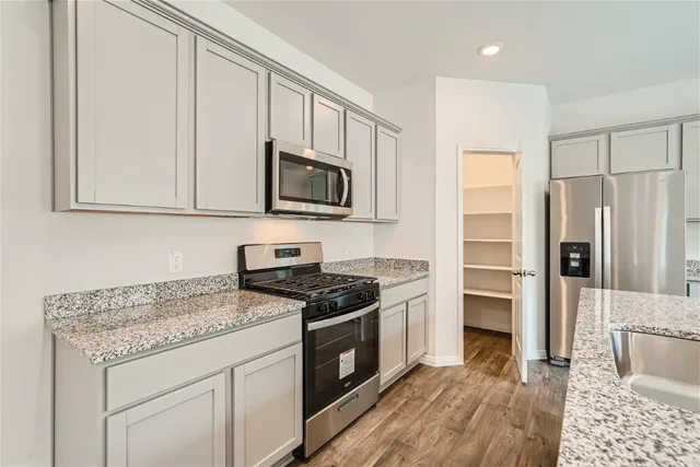 a kitchen with granite countertop a sink stove and refrigerator
