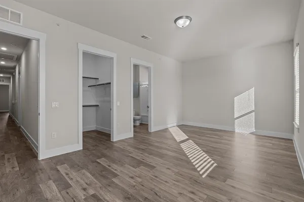 a view of empty room with wooden floor and fan