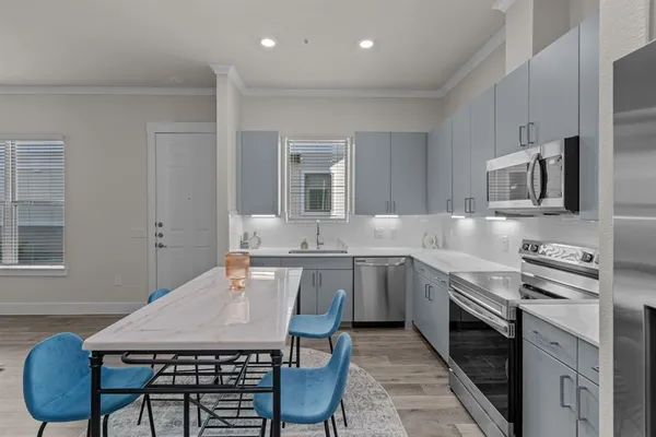 a kitchen with stainless steel appliances a stove a sink a microwave a refrigerator and cabinets