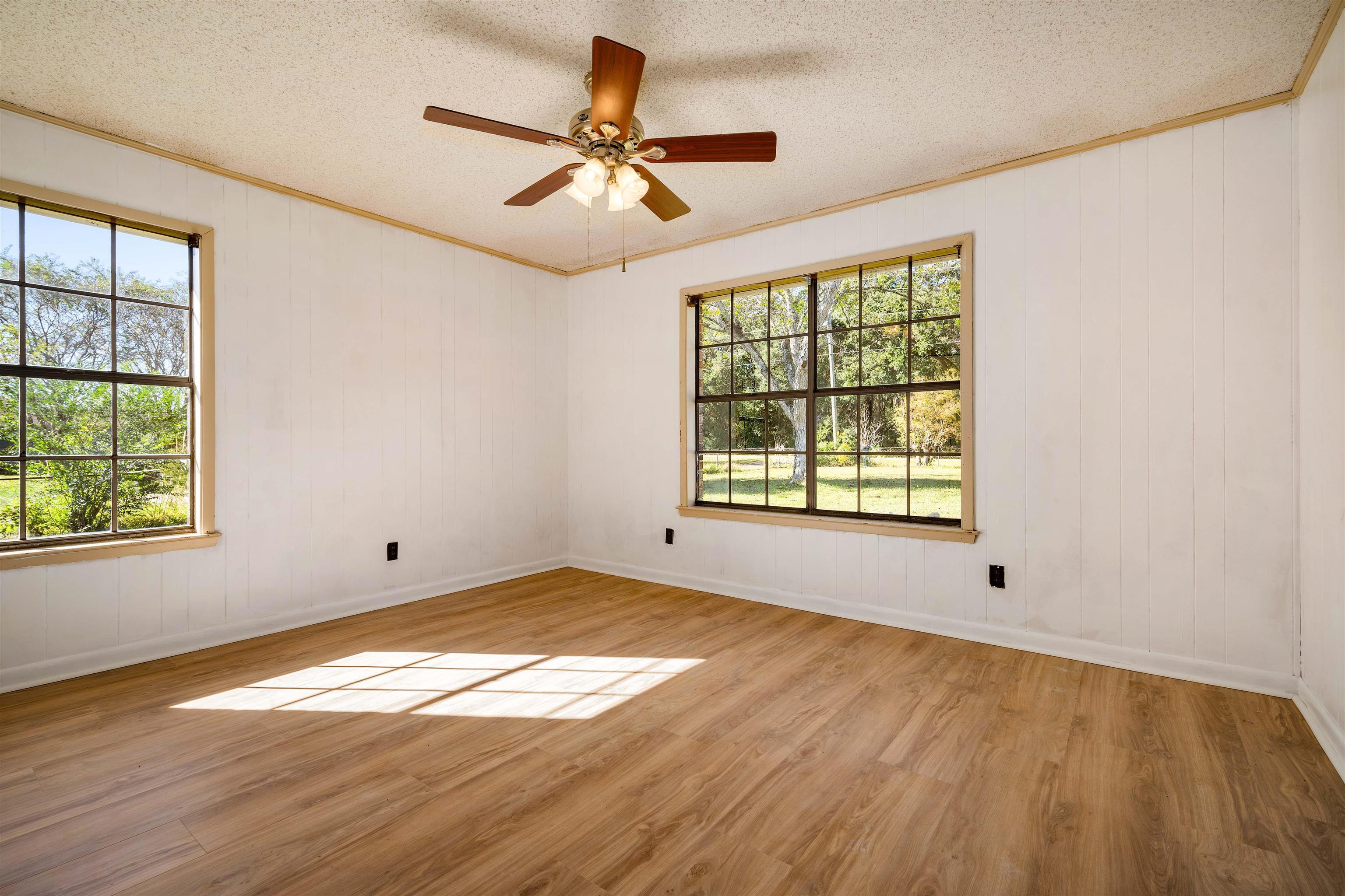 10285 Argyle Road Irvington, AL 36544 - Photo 19 of 28 Unfurnished room with light wood finished floors, crown molding, a textured ceiling, a ceiling fan, and wood walls