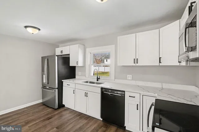 a kitchen with stainless steel appliances a sink a stove a refrigerator and cabinets