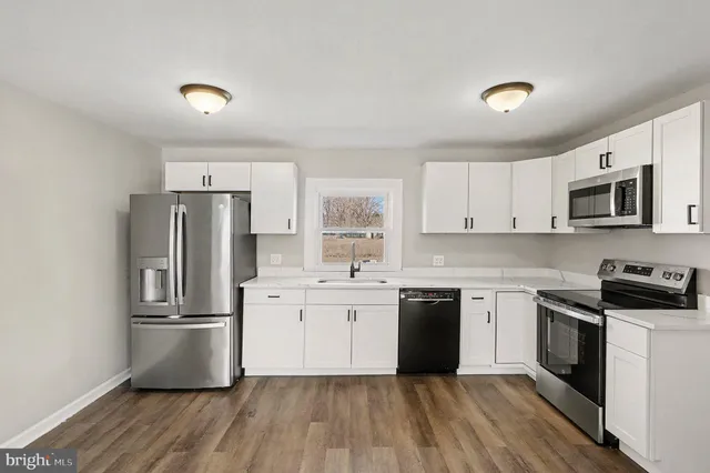 a kitchen with stainless steel appliances granite countertop a stove top oven a refrigerator and white cabinets