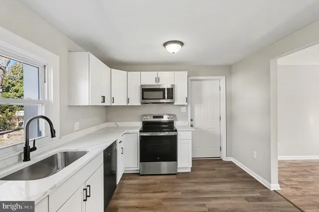 a kitchen with granite countertop white cabinets and stainless steel appliances