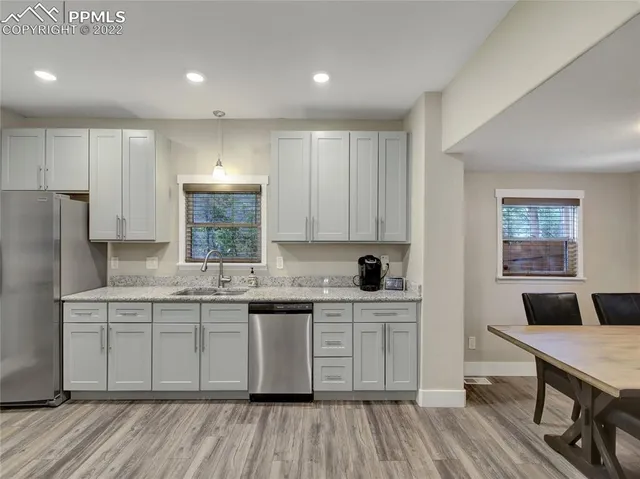 a kitchen with a sink dishwasher a stove and white cabinets with wooden floor