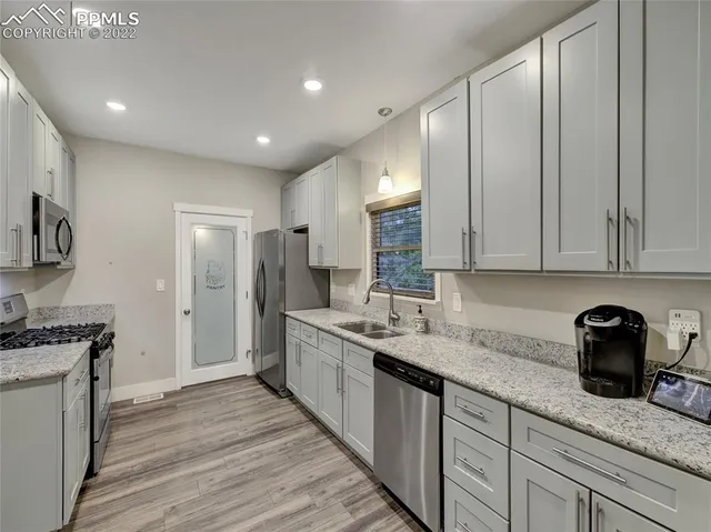 a kitchen with granite countertop kitchen island stainless steel appliances a sink stove top oven and cabinets