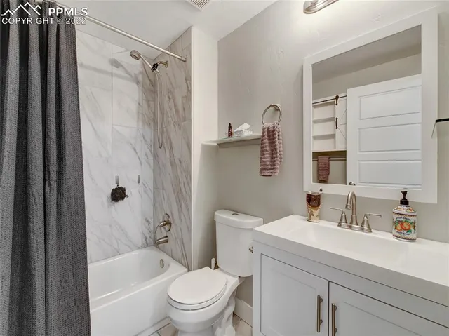 a bathroom with a granite countertop bathtub shower sink vanity and toilet