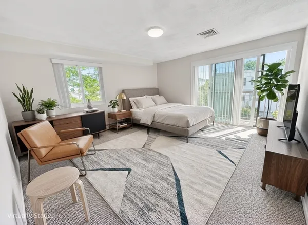 a spacious bedroom with a bed a couch and a large window