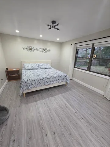 a spacious bedroom with a bed and a dresser with wooden floor