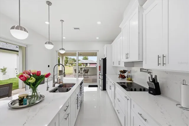a kitchen with stainless steel appliances kitchen island granite countertop a stove a sink and a white cabinets