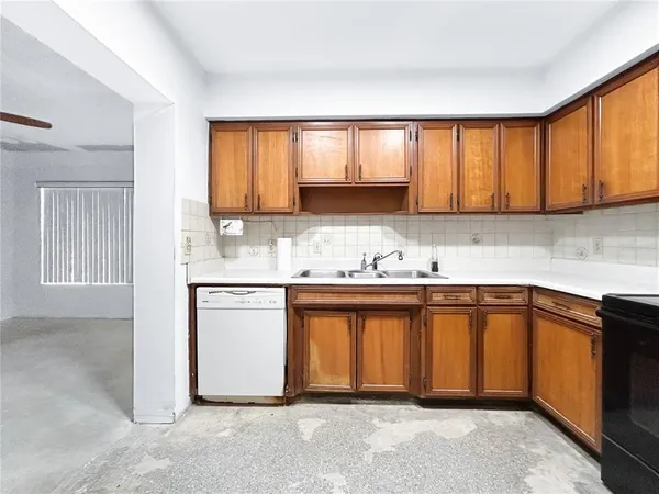 a view of a kitchen with a sink and dishwasher a stove top oven with wooden floor