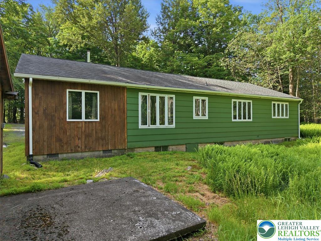 143 Logger Road Canadensis, PA 18325 - Photo 22 of 32 A vibrant green facade with natural wood accents creates a harmonious blend with the surrounding woodland.