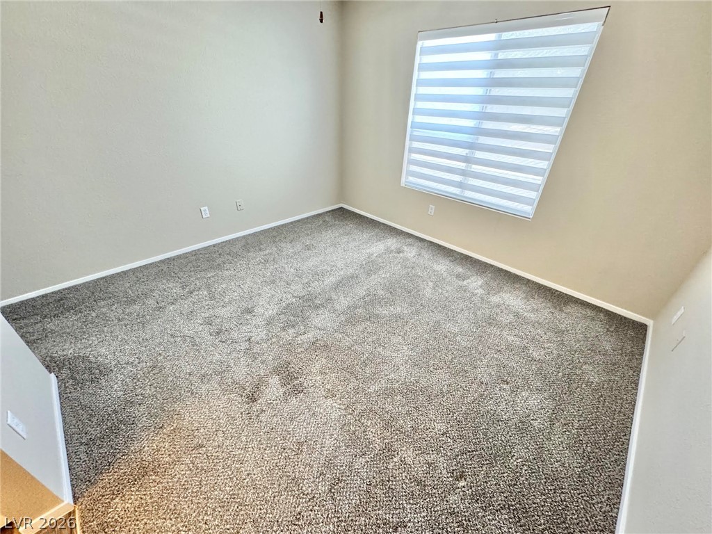 8070 West Russell Road, Unit 2121 Las Vegas, NV 89113 - Photo 16 of 22 Well-lit room featuring soft carpeting and an angled window.