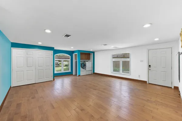 a view of an empty room with a window and wooden floor