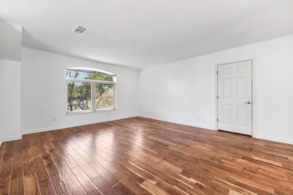 an empty room with wooden floor and windows