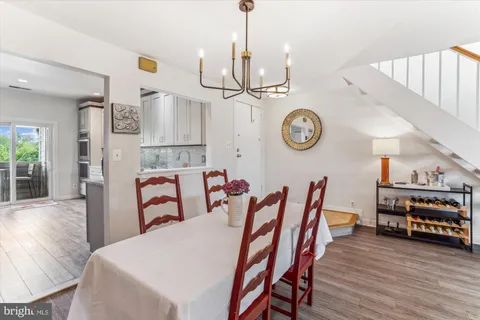 a view of a dining room and livingroom with furniture wooden floor clock and a chandelier