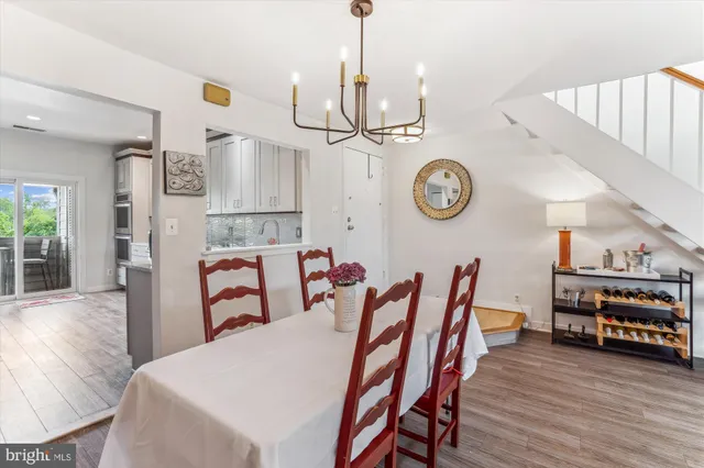 a view of a dining room and livingroom with furniture wooden floor clock and a chandelier